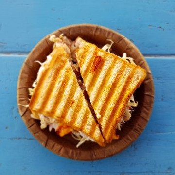 Overhead shot of a toasted sandwich on a plate, cut in triangles, on a blue surface