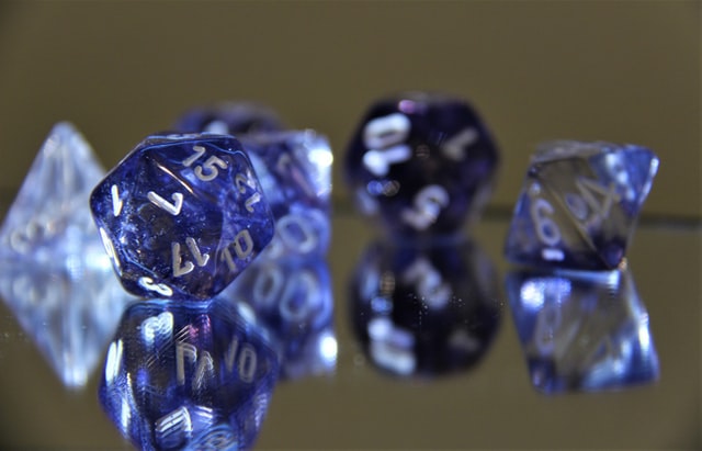 Set of translucent purple gaming dice on a glass surface.