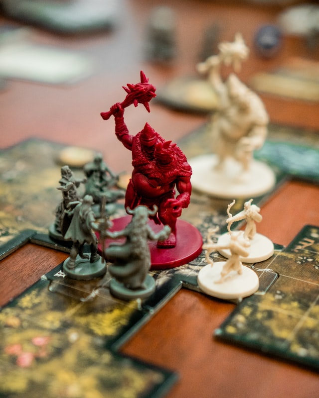 Ettin mini surrounded by hero minis on tabletop board game.